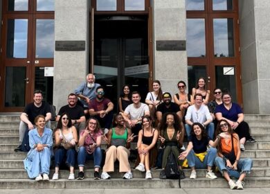 Large group of PR professionals sitting in three rows on stairs, posing for a picture.