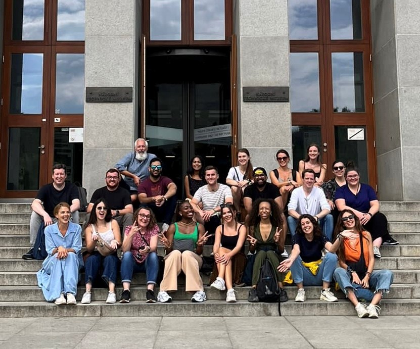 Large group of PR professionals sitting in three rows on stairs, posing for a picture.