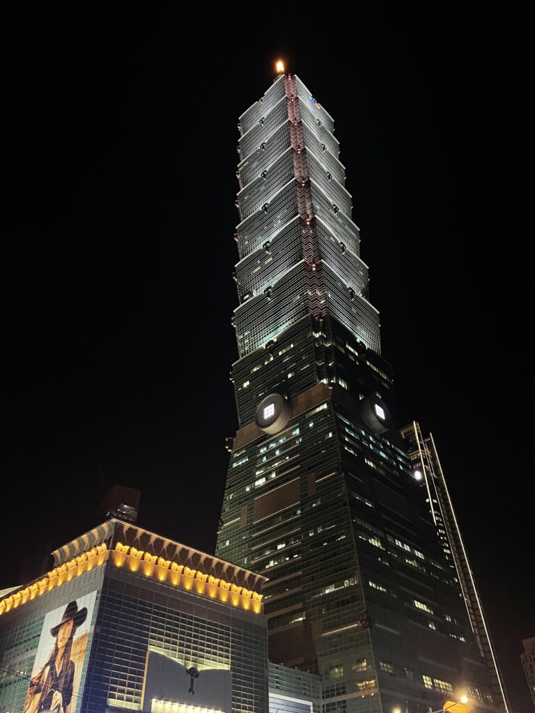 A tall, illuminated skyscraper against a black sky.