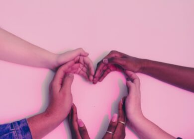 Hands of diverse skin tones forming a heart