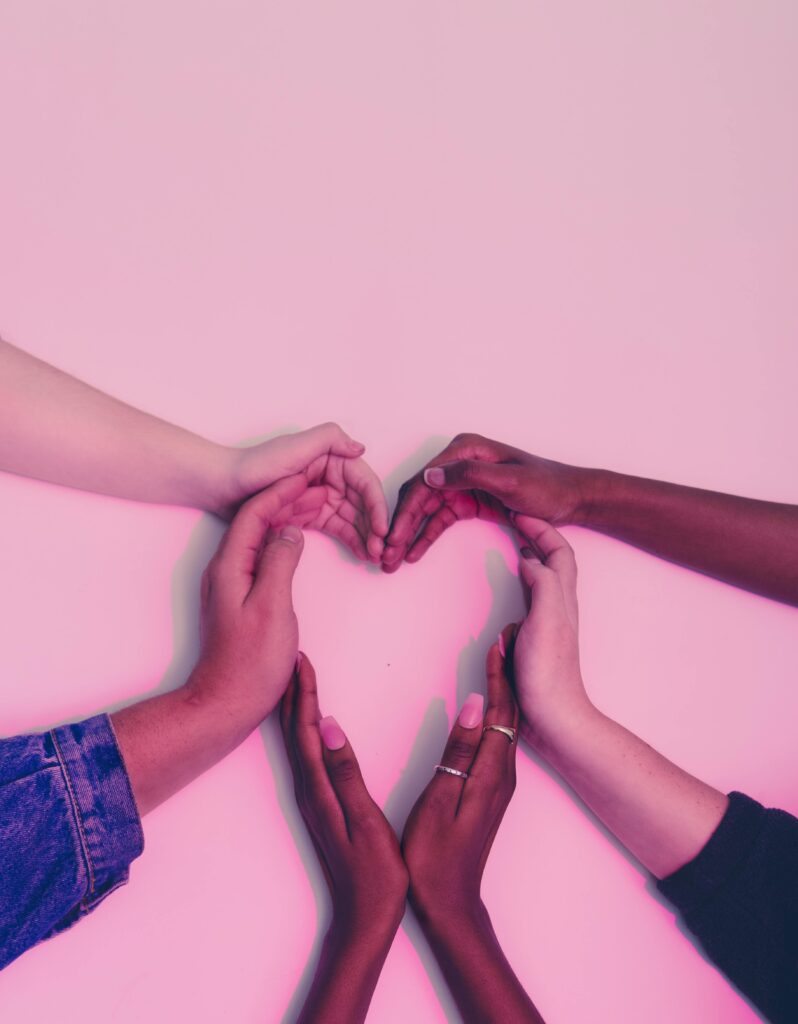 Hands of diverse skin tones forming a heart