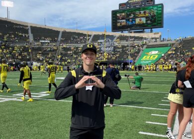 Man standing on football field holding his hands in the shape of an O.