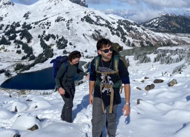 Man and woman hiking on snowy mountain trail.